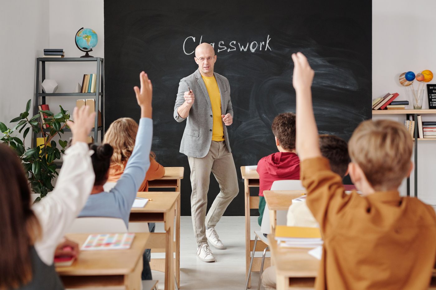 keychain gift for teacher — Teacher interacting with students raising hands in a classroom setting