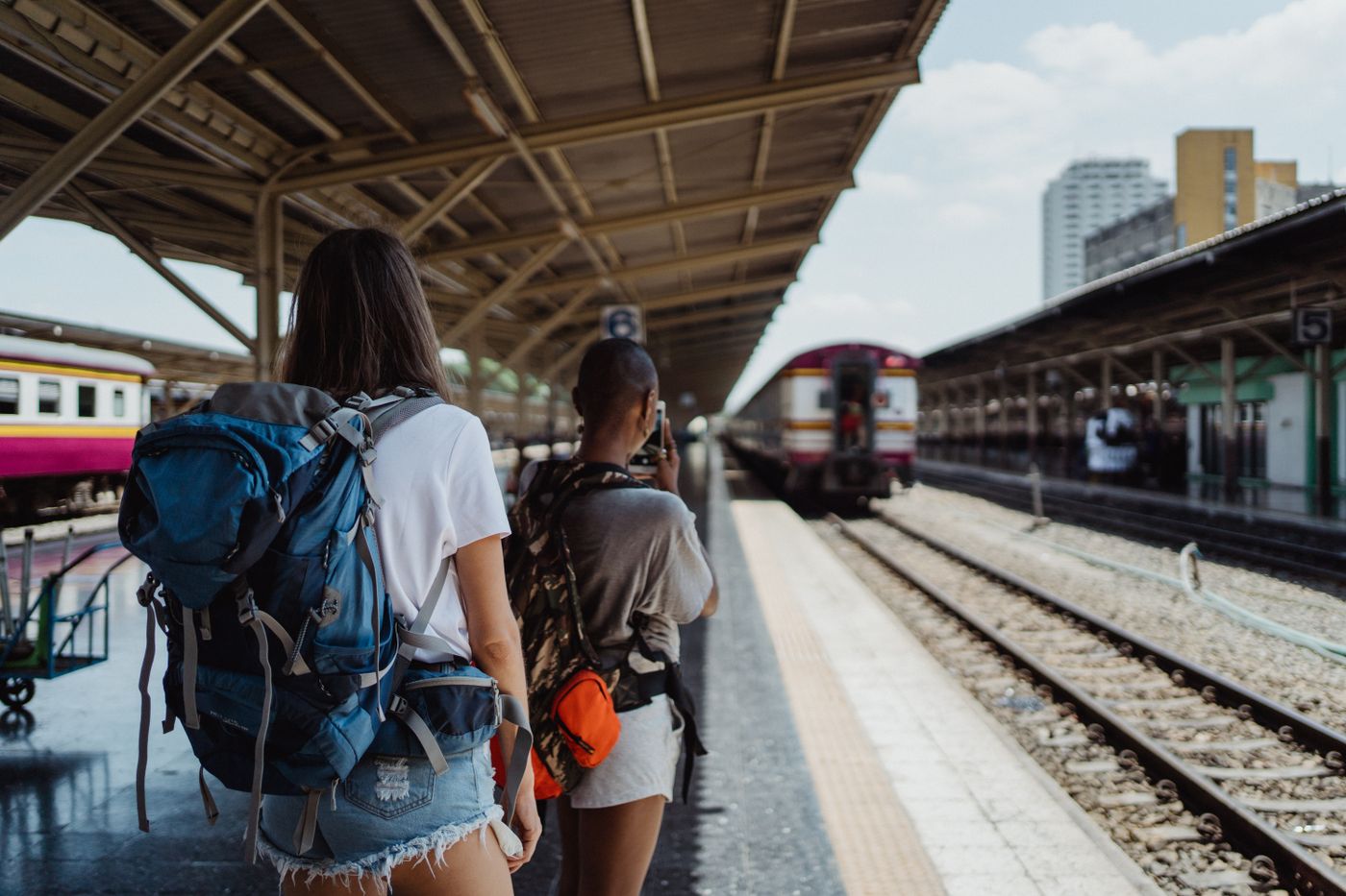 name tag keychain for backpack — Two backpackers waiting at a railway station, ready for their travel adventure