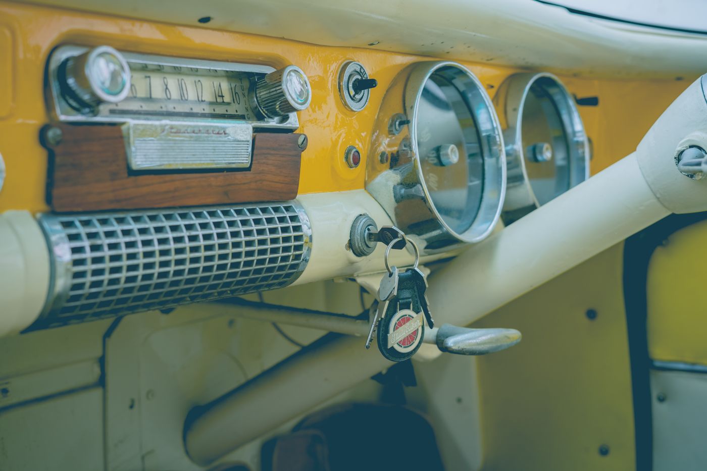 name keyring number plate — Close-up of a classic vintage car dashboard featuring an analog radio, speedometer, and keys