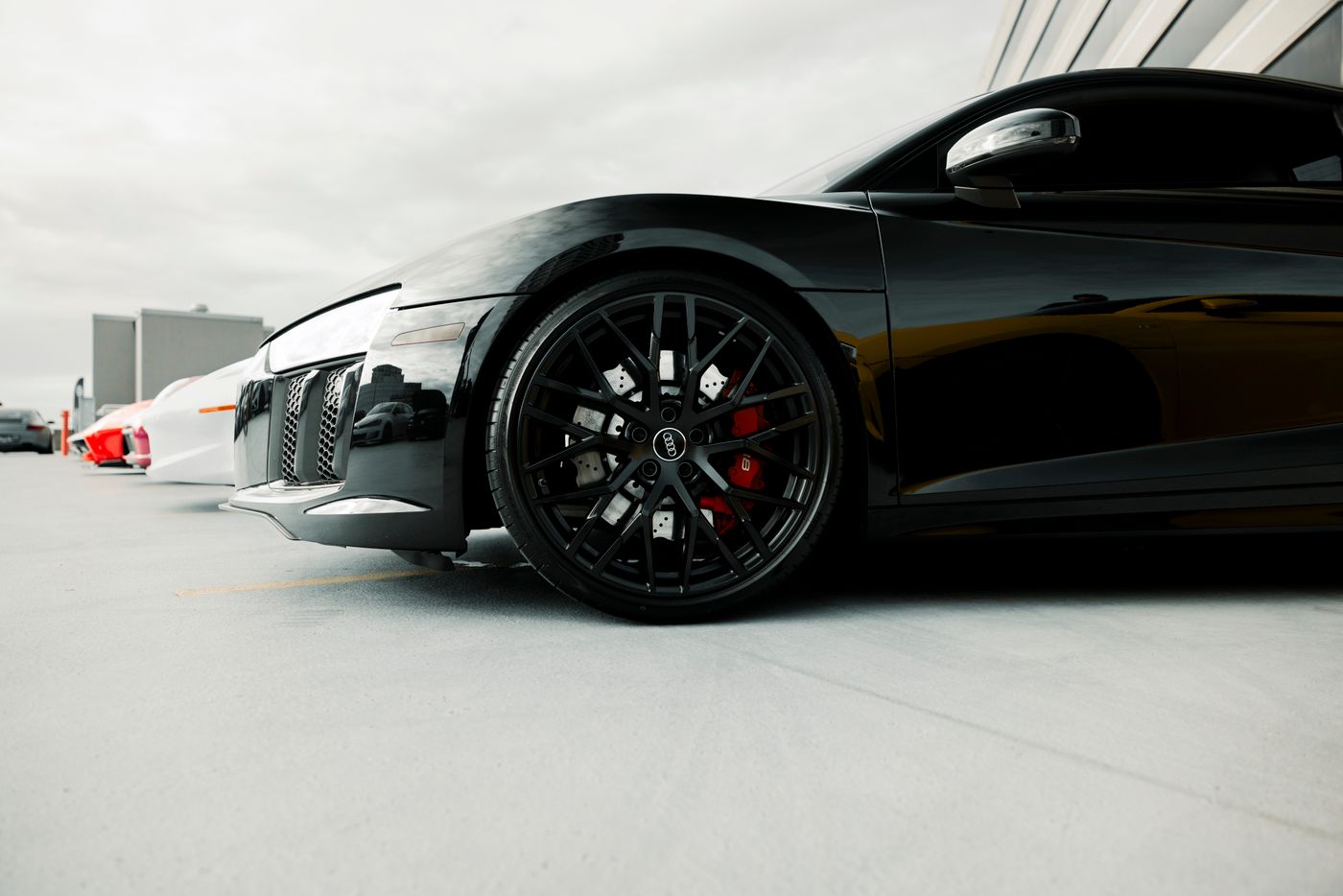 name keyring number plate — Close-up of a black luxury sports car's wheel detail in an outdoor setting