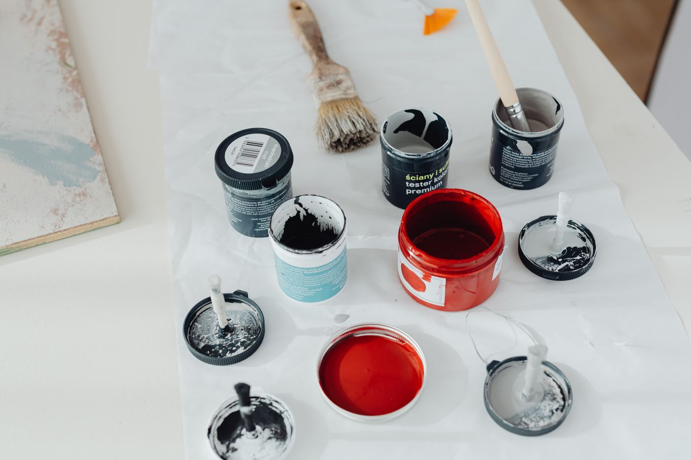 can you paint 3d printed items — Assorted paint cans and brushes arranged on a white surface, perfect for artistic projects