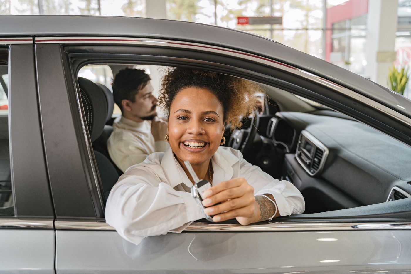 cartoon stickers for car — Joyful couple in their new car, holding keys in a dealership showroom, smiling warmly