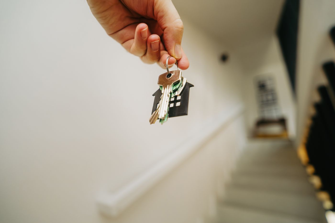 name keychain for water bottle — Close-up of a hand holding a keychain in the shape of a house, symbolizing real estate and property ownership