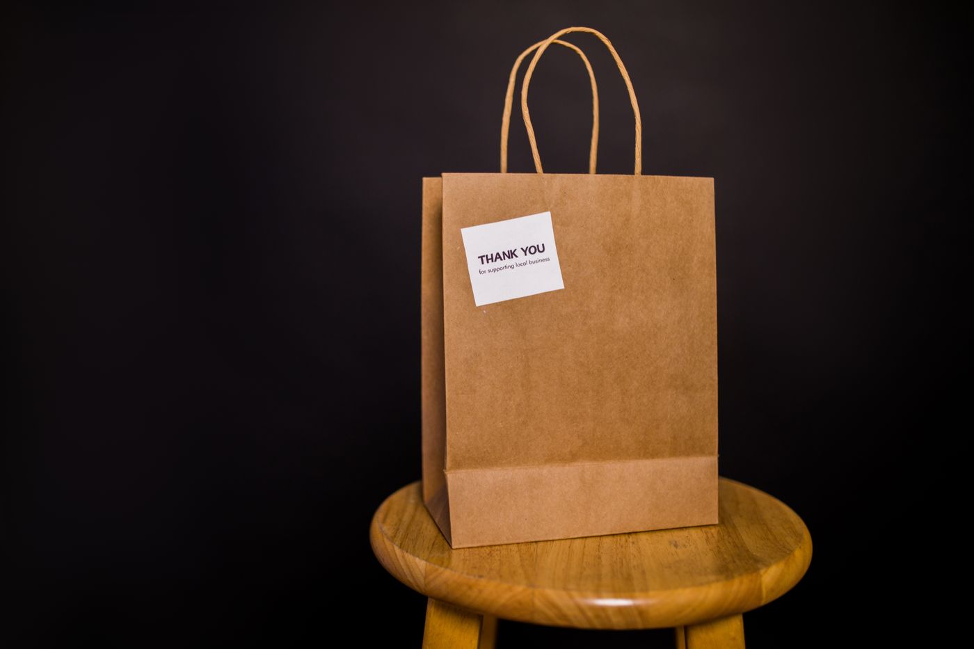 cartoon stickers for wall — Brown paper bag with thank you note placed on a wooden stool against a black background