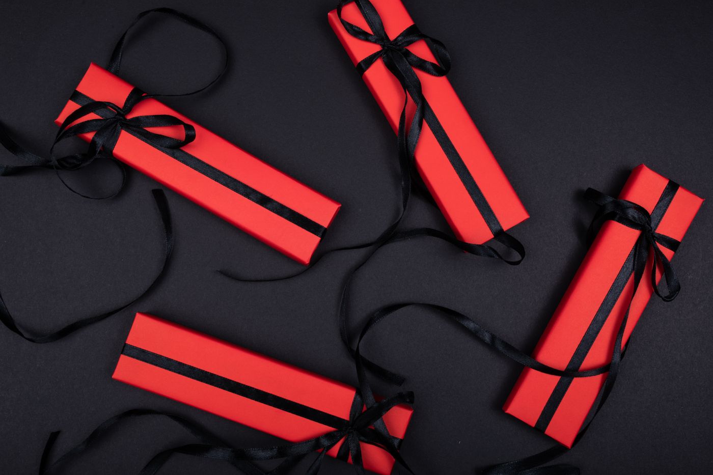 keychain gift for brother — Top view of red gift boxes with black ribbons arranged on a black background