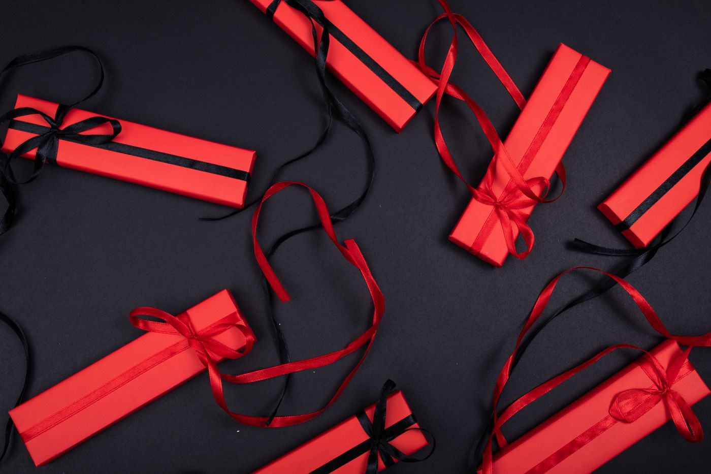 keychain gift for brother — Red gift boxes with black ribbons arranged on a black background, captured from above