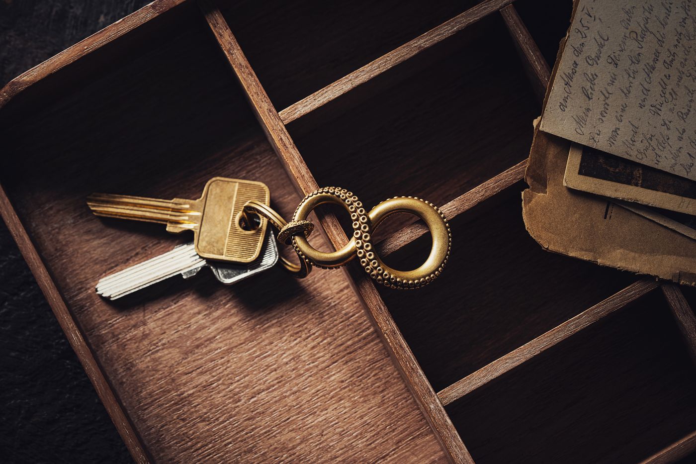 personalised keychain for house — A vintage keyring with brass keys in a wooden box next to old letters for a nostalgic feel