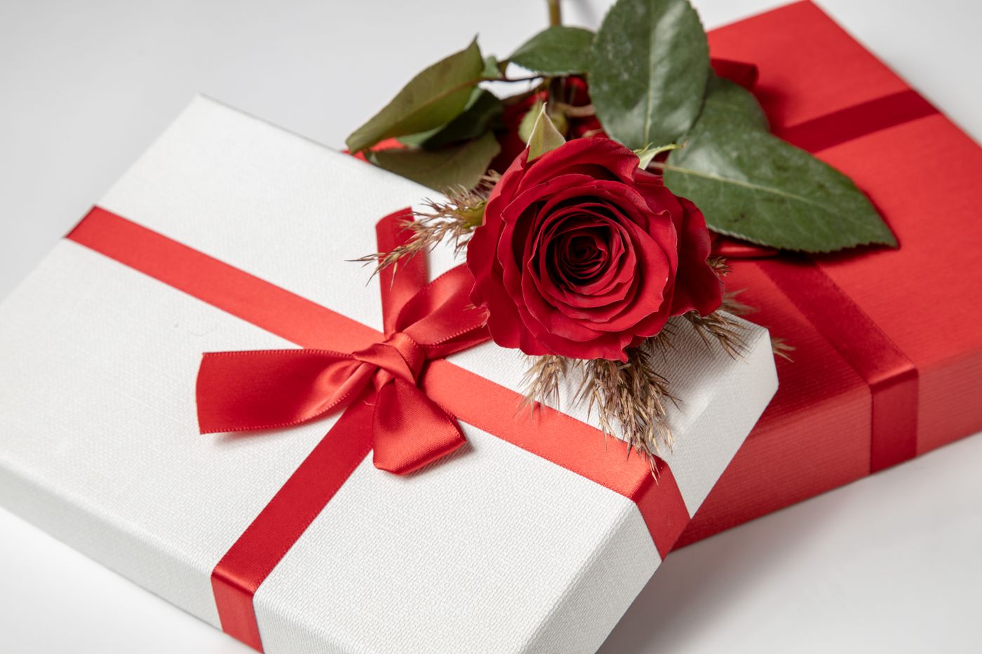 3d printer accessories gift — Close-up of red rose atop elegantly wrapped gift boxes with red ribbons, perfect for gift-giving occasions