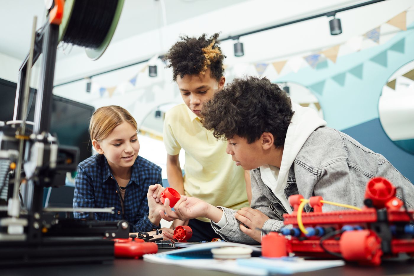 3d printed house cons — Concentrated group of children sitting at table and exploring new engineering device together in light room