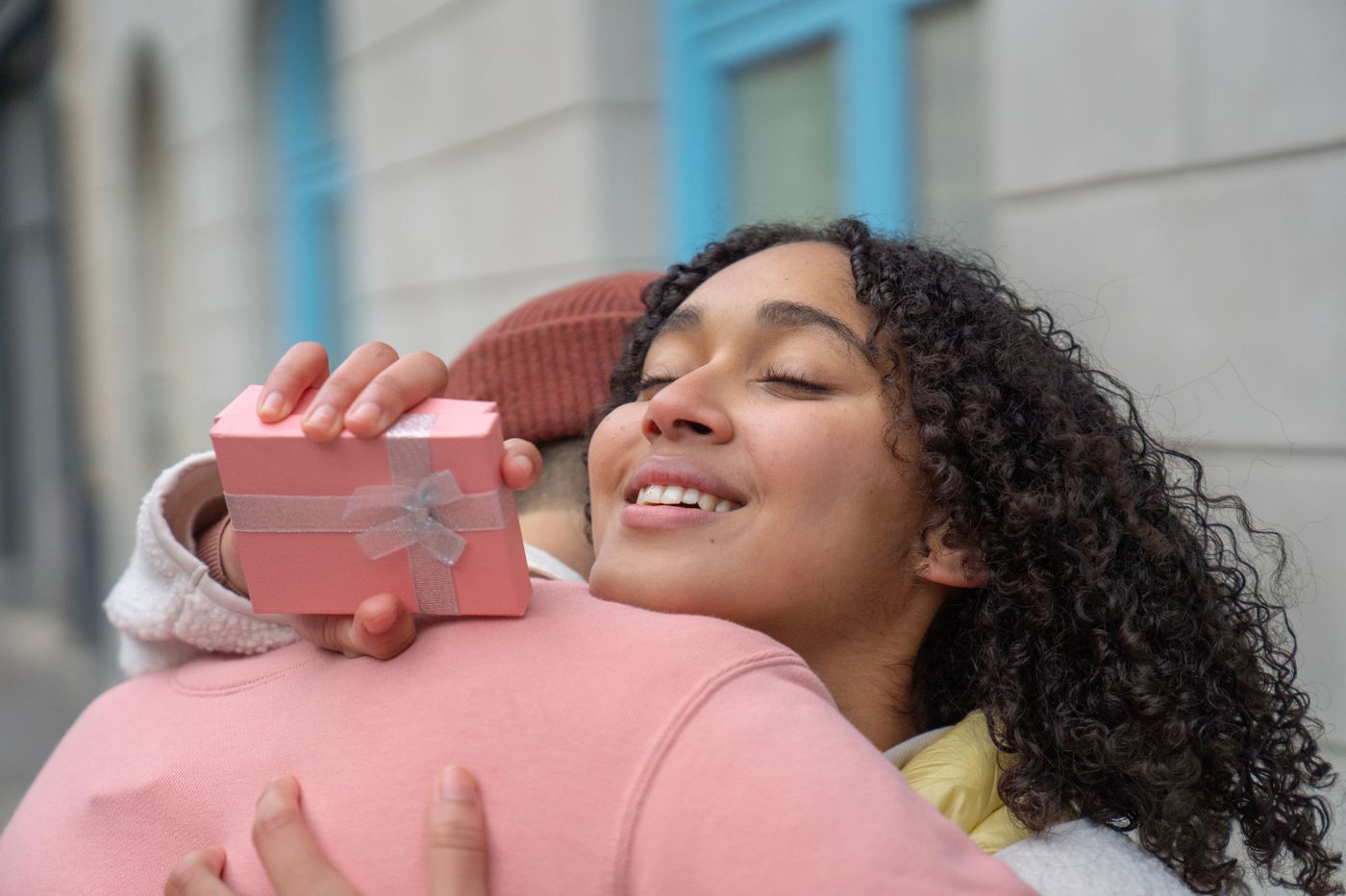 3d printed gift for girlfriend — Content Hispanic girlfriend with gift box in hand embracing anonymous boyfriend while standing on street on blurred background 