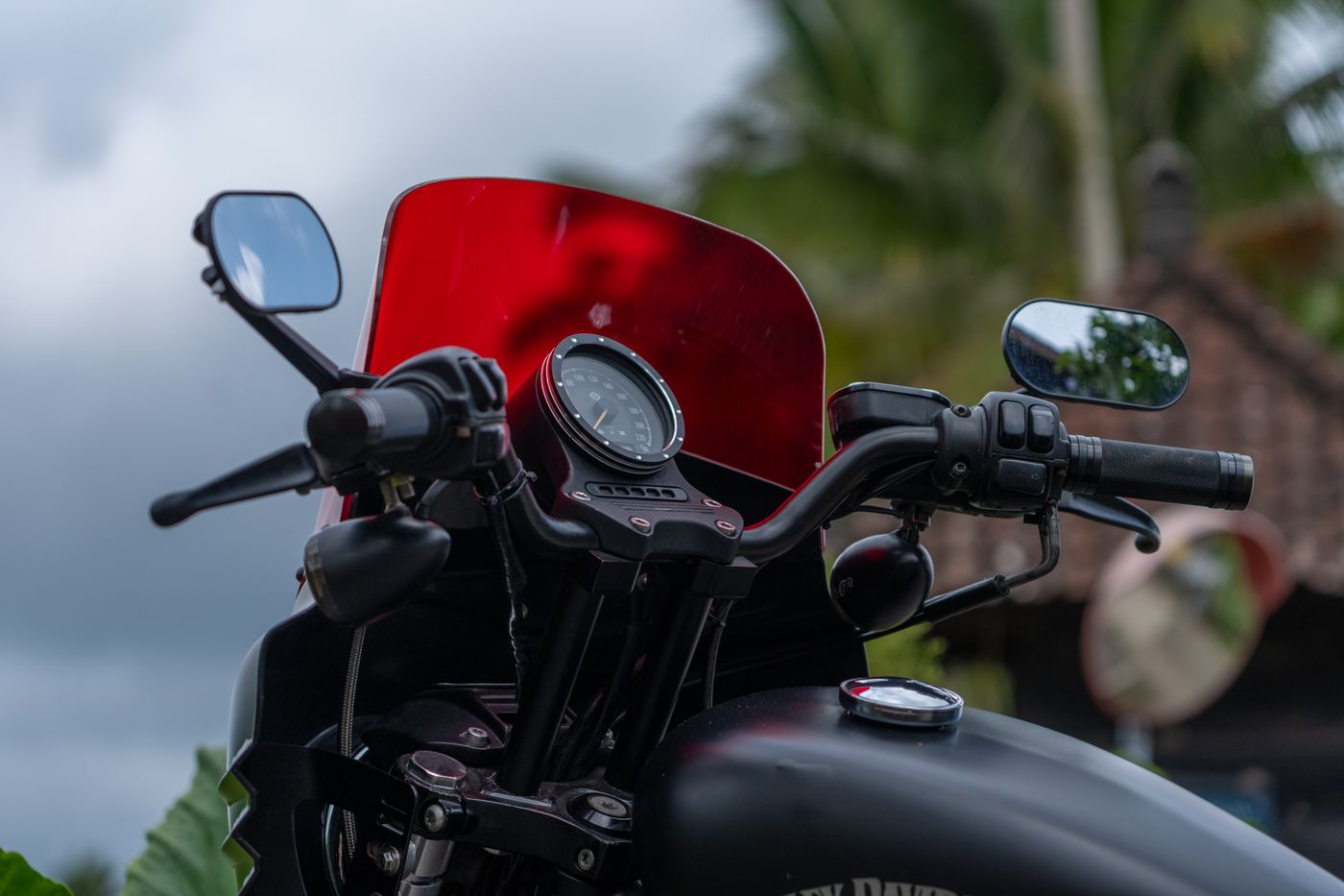 3d printed accessories for motorcycle — Close-up of a motorcycle's handlebars and red windshield, outdoors