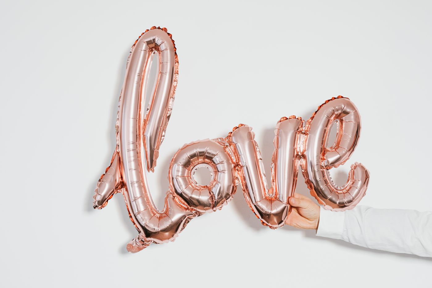 3d printed engagement gift ideas — A rose gold balloon spelling 'love' held by a hand against a white backdrop, capturing affection and celebration