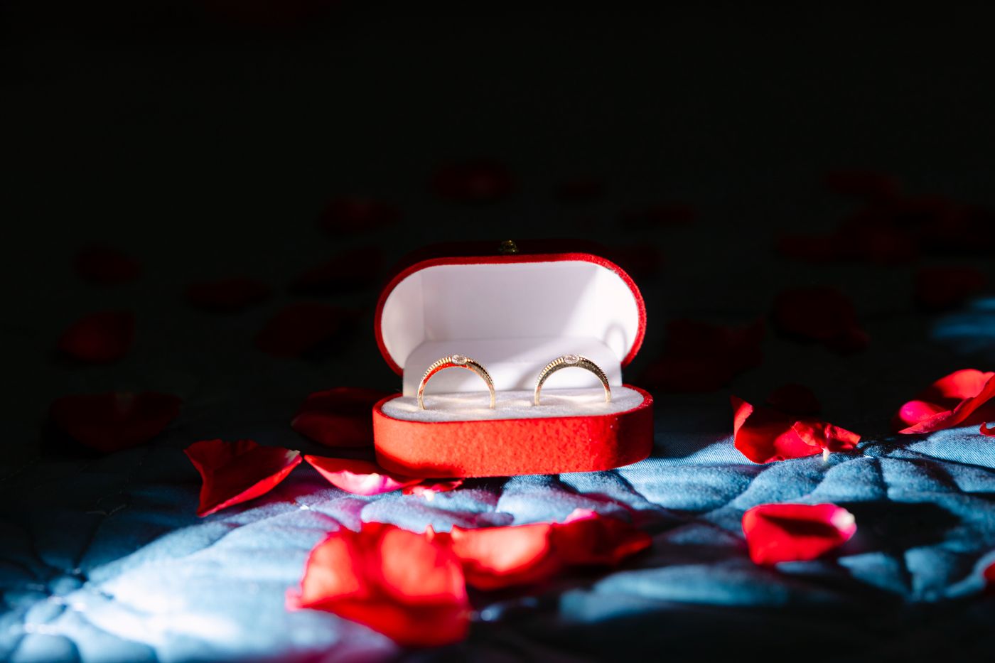 3d printed engagement gift ideas — A pair of gold rings inside a red velvet box surrounded by rose petals, symbolizing romance