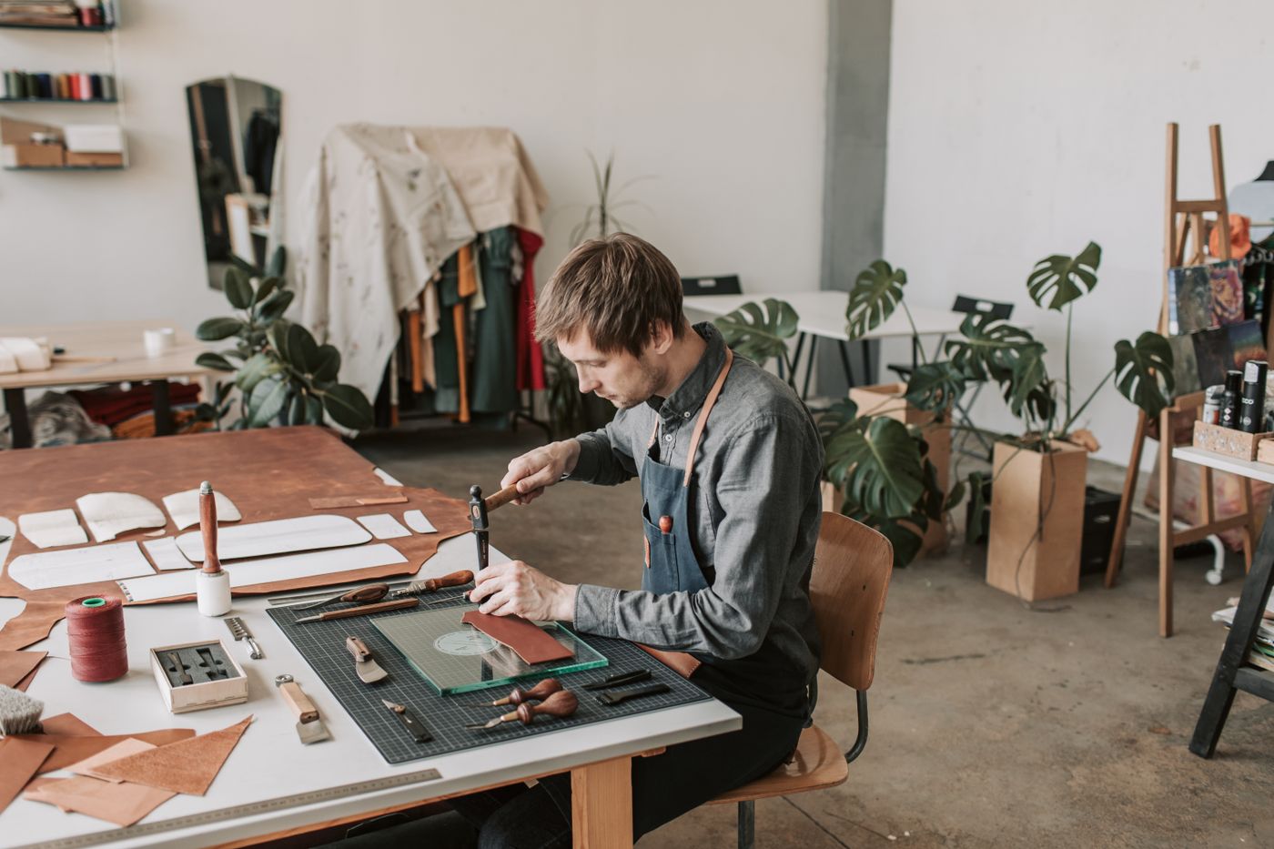 cheap custom shape stickers — Leather craftsperson working at a table in a stylish workshop