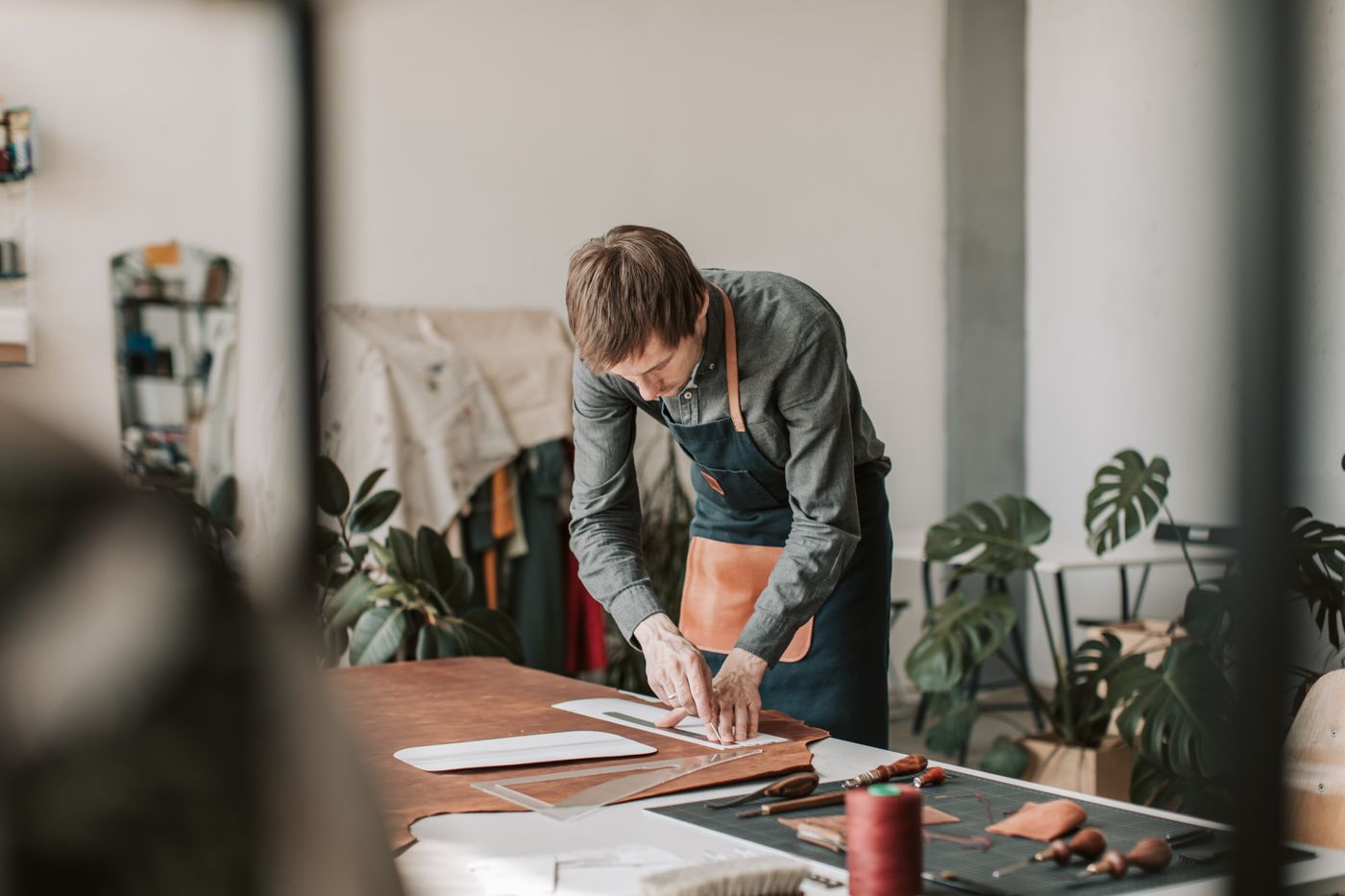 cheap custom shape stickers — A skilled artisan measuring leather in a workshop, focused on handcrafted perfection