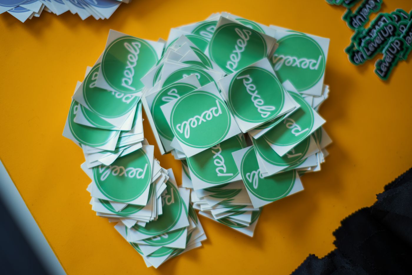 how to print custom shape stickers — A collection of green Pexels stickers neatly stacked on a vibrant yellow background