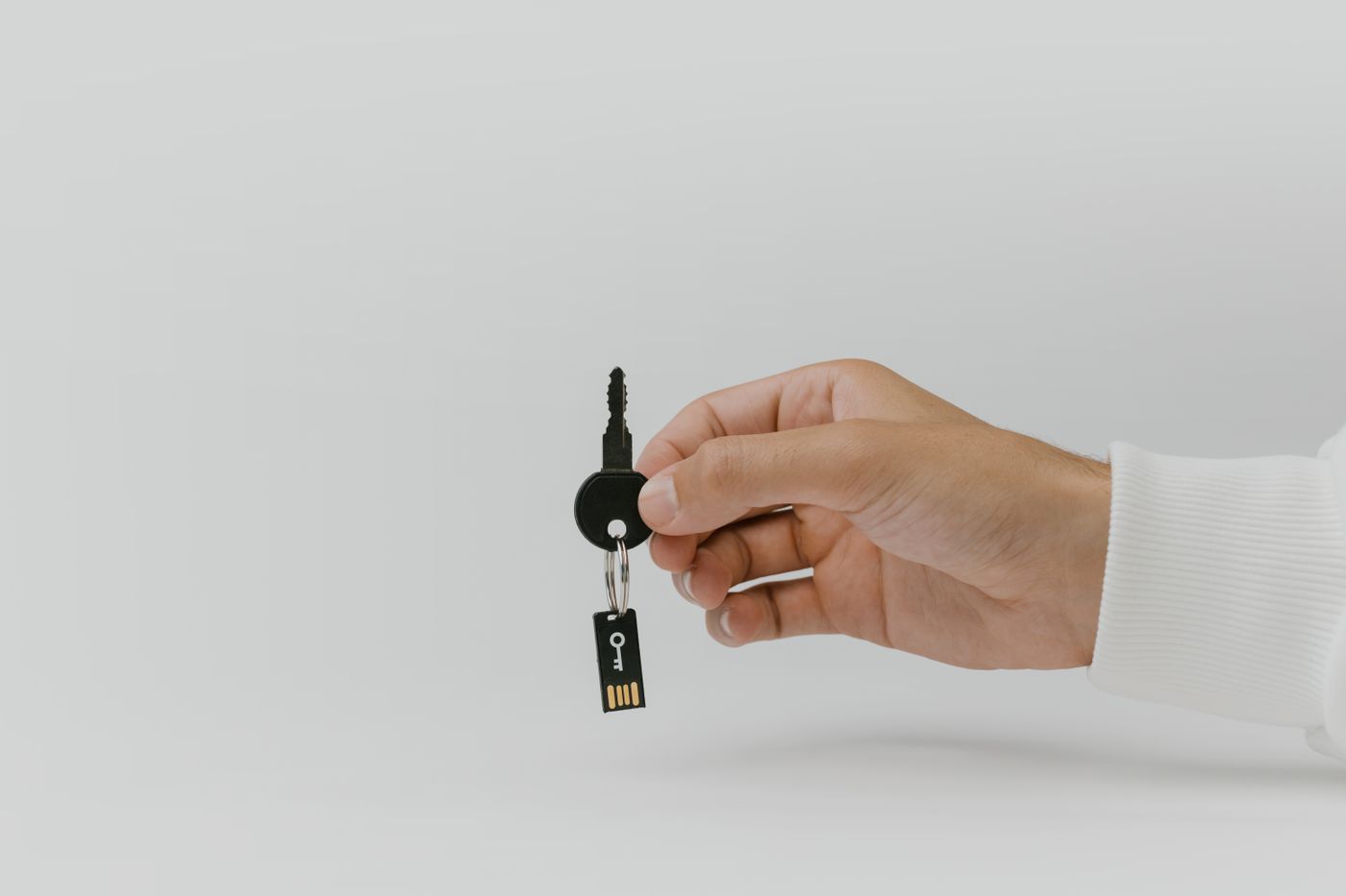 name keychain maker online — Hand holding keychain with integrated USB flash drive against a plain background