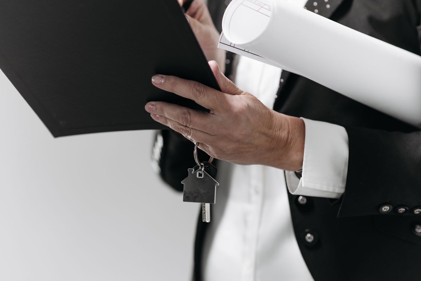 name keychain maker online — Close-up of a business professional holding a house key and architectural plans, symbolizing real estate