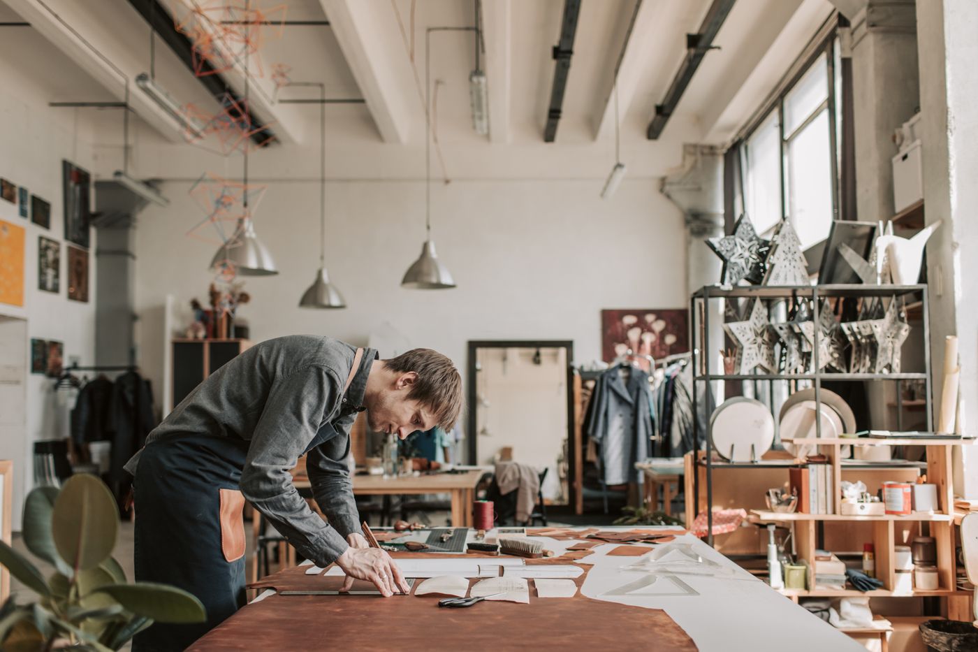 3d printer keychain price — A man diligently crafting leather goods in a bright, organized workshop, emphasizing traditional craftsmanship