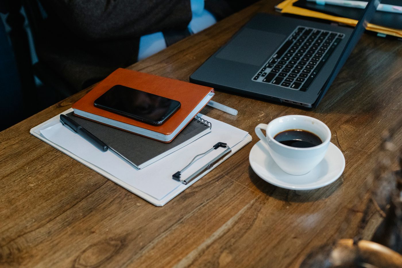 3d printed phone stand — From above of opened laptop with cup of coffee placed on wooden table near notebooks and smartphone in office