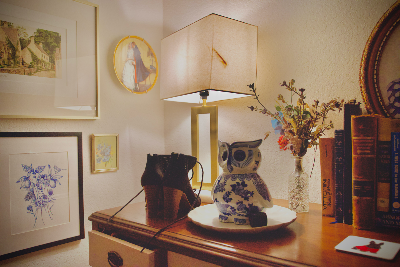 3d printed lamp — A vintage desk with artistic decor, featuring a lamp, owl figurine, and framed art prints