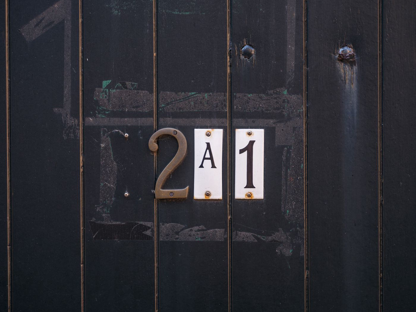 house name plate 3d printed — Close-up of a dark wooden door with vintage-style number signage displaying '2A1'
