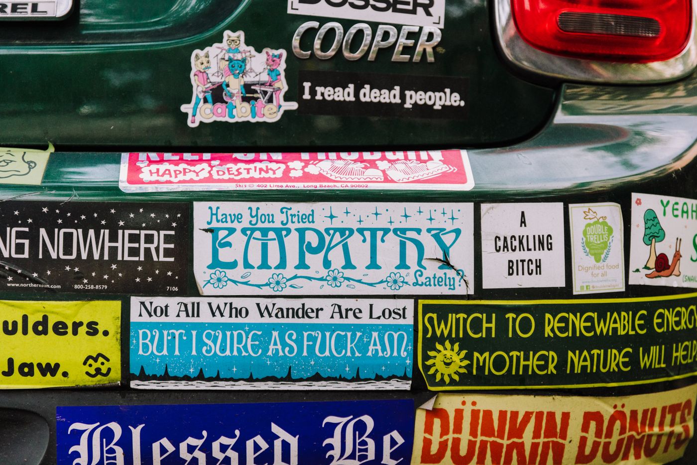 bumper stickers india — Close-up of diverse, humorous bumper stickers covering a car's rear, showcasing urban creativity