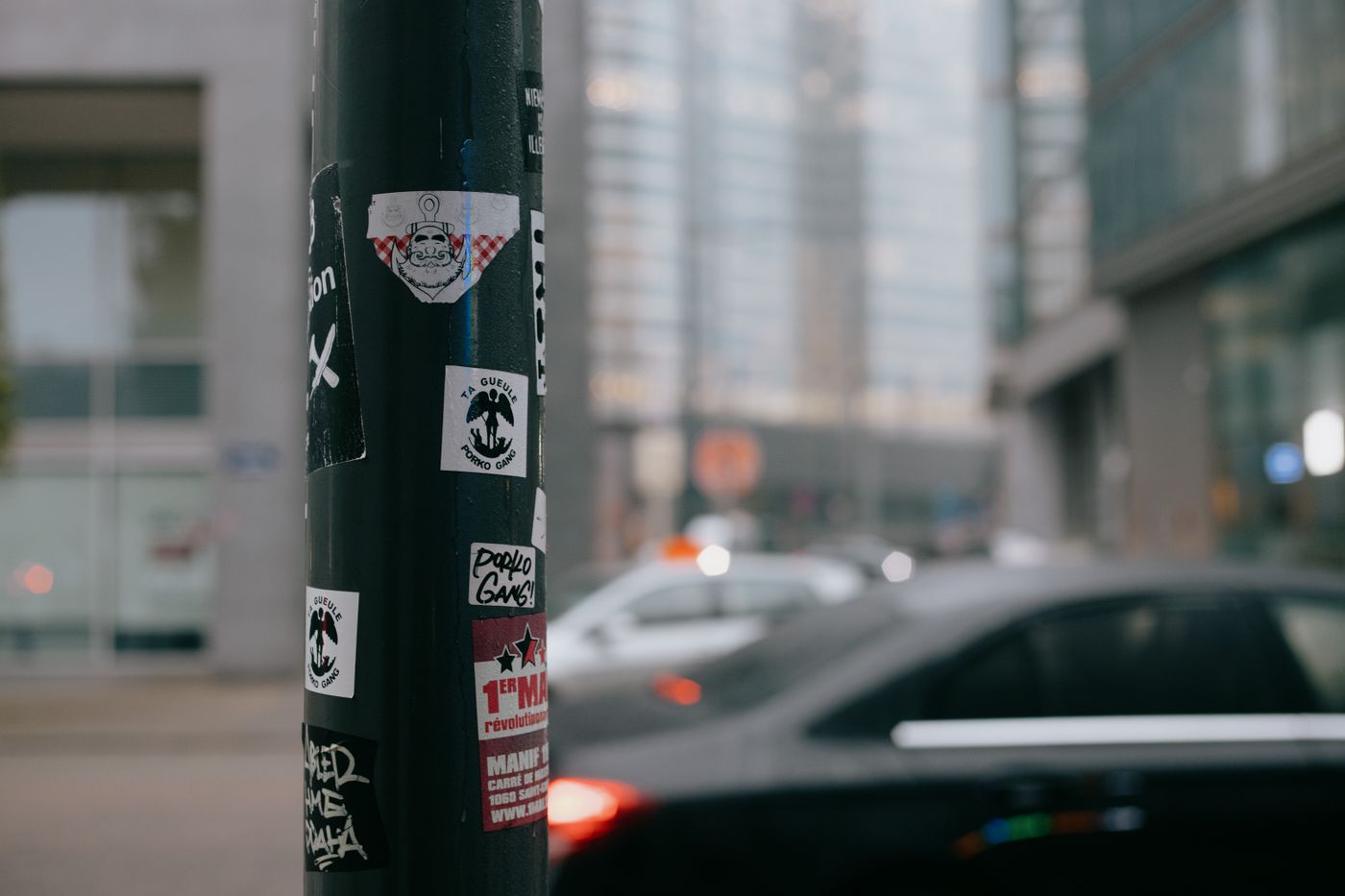 bumper stickers india — Various stickers attached to lamppost near road with different cars in modern city district on overcast day