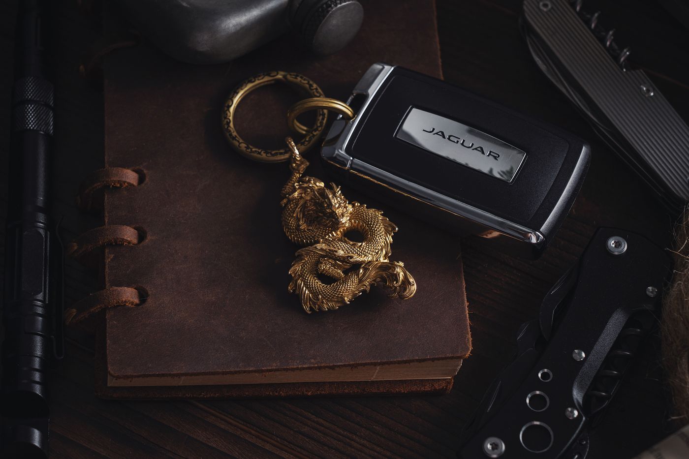 anime keychain — Stylish still life featuring a dragon keychain, luxury car key, and retro notebook on a rustic surface