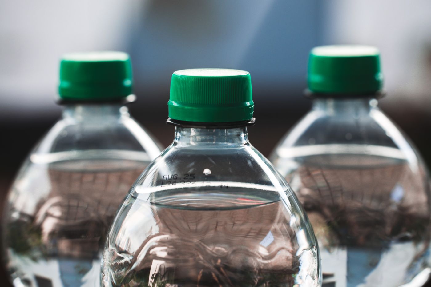 sticker for water bottle — Focused view of three clear plastic bottles with green caps outdoors