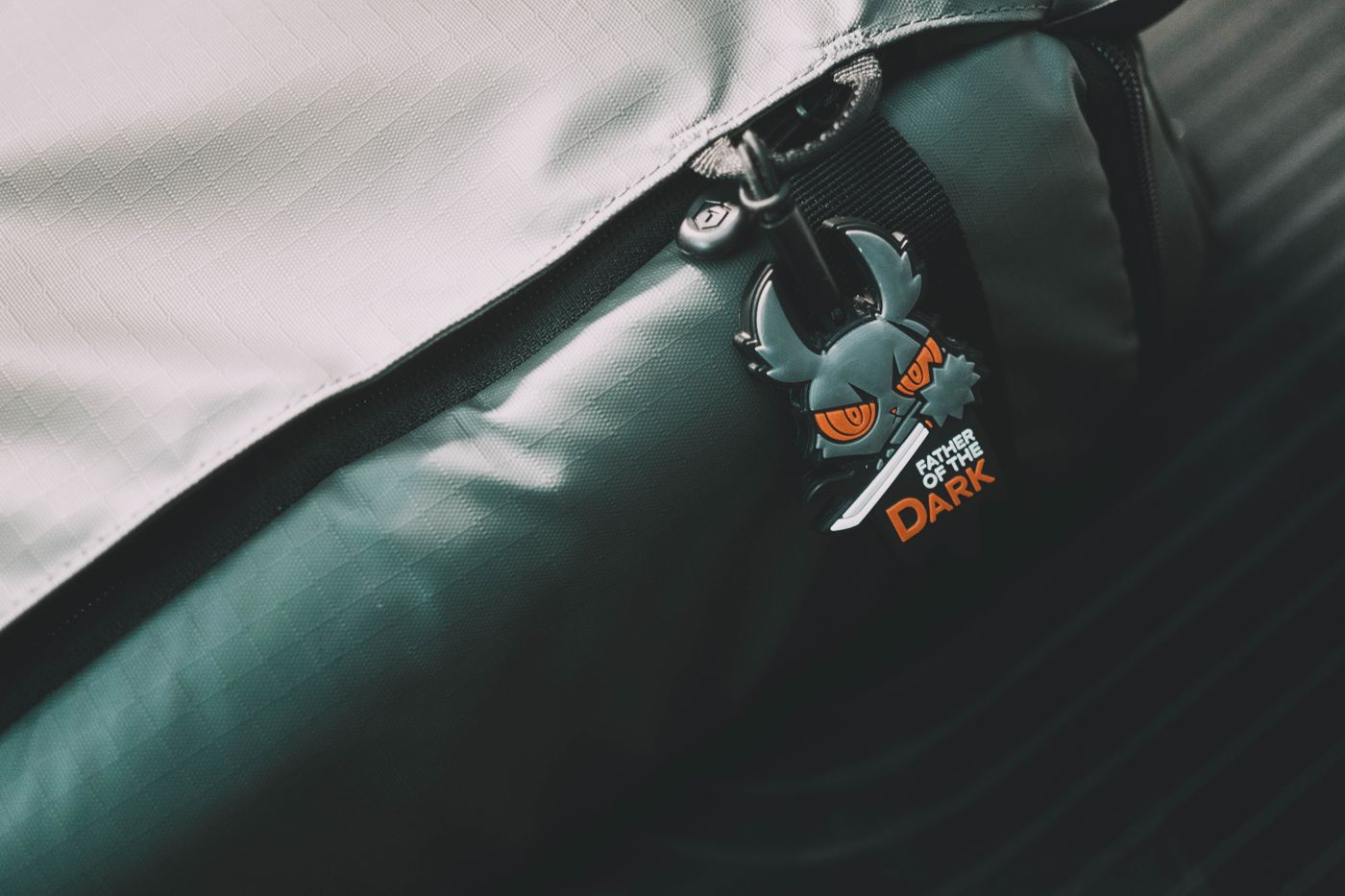 gaming keychain — Close-up of a backpack zipper adorned with a unique dark emoji-themed keychain. A blend of style and personality
