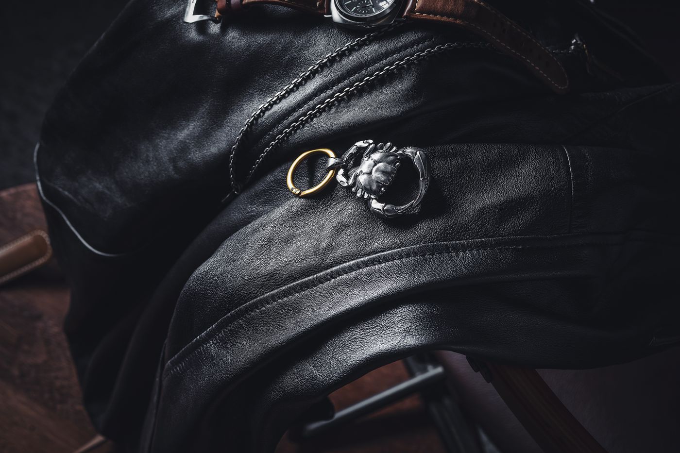 gaming keychain — Stylish leather draped with a silver keychain and wristwatch in a moody setting