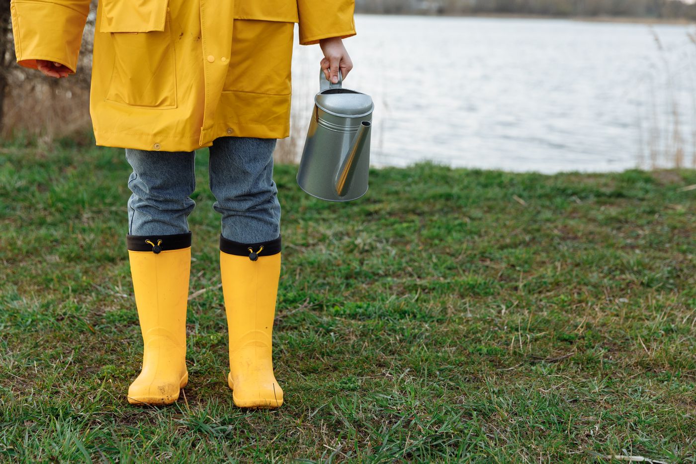 is pla waterproof — Person wearing yellow rain gear and holding a watering can by the lake
