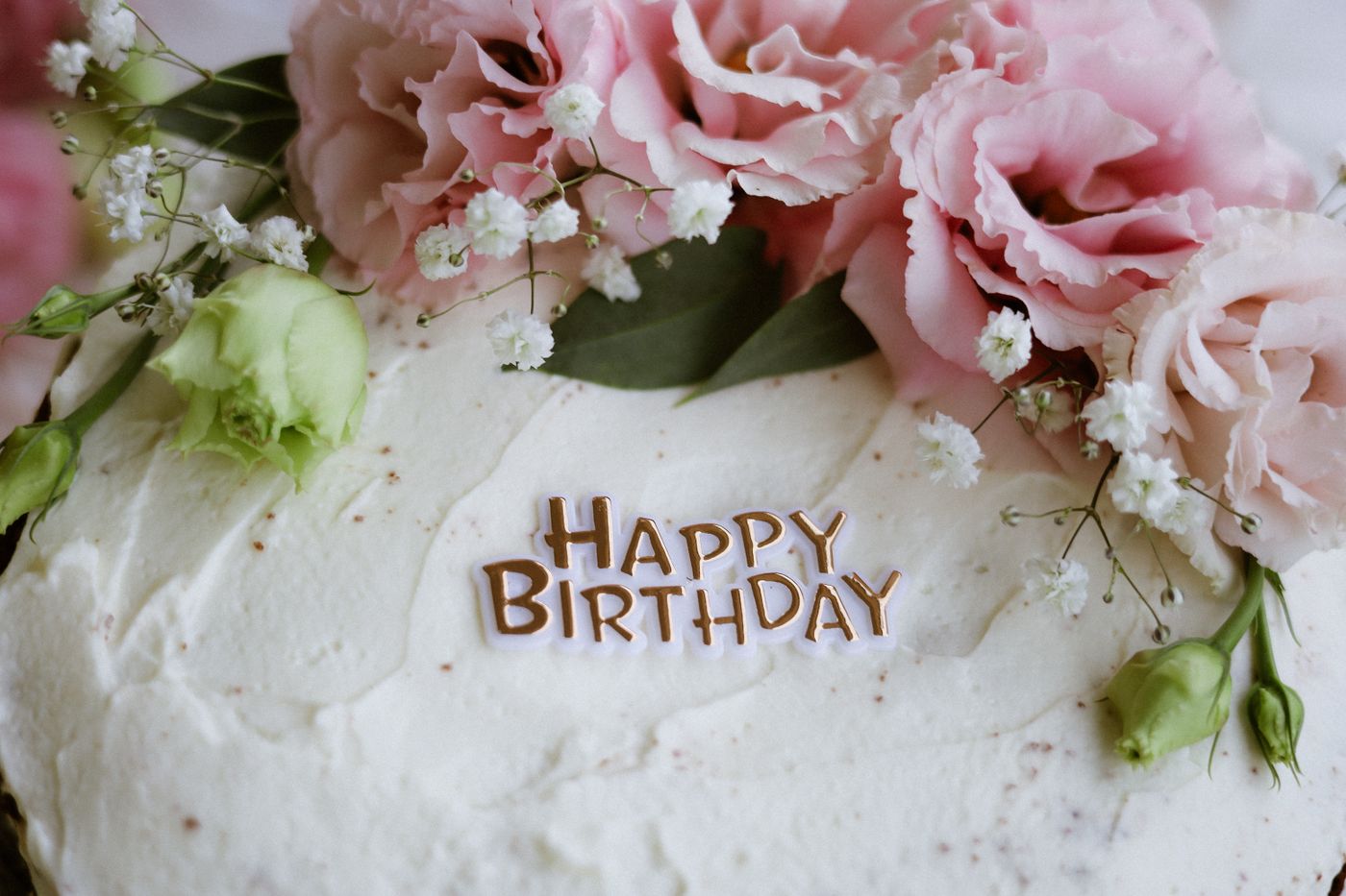 3d printed cake topper — Close-up of a birthday cake decorated with pink flowers and 'Happy Birthday' text