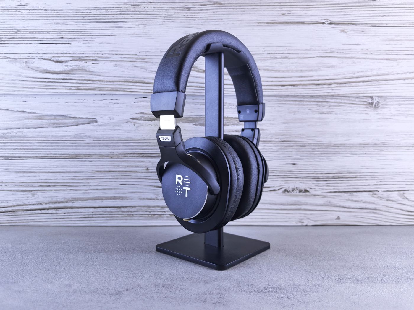 3d printed headphone stand — Stylish black headphones on a stand with wooden texture background