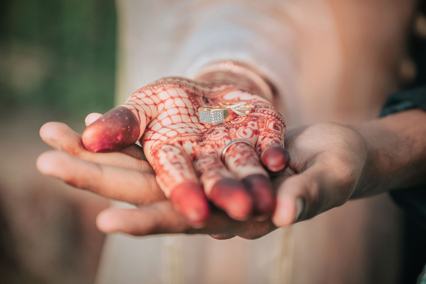 3d printed jewellery — Close-up of hands with mehndi designs holding wedding rings, symbolizing engagement in India
