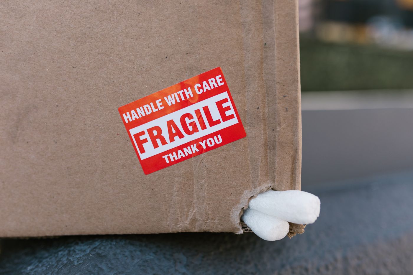 vinyl sticker printing — Close-up of a cardboard box with a 'fragile' sticker and packing peanuts visible