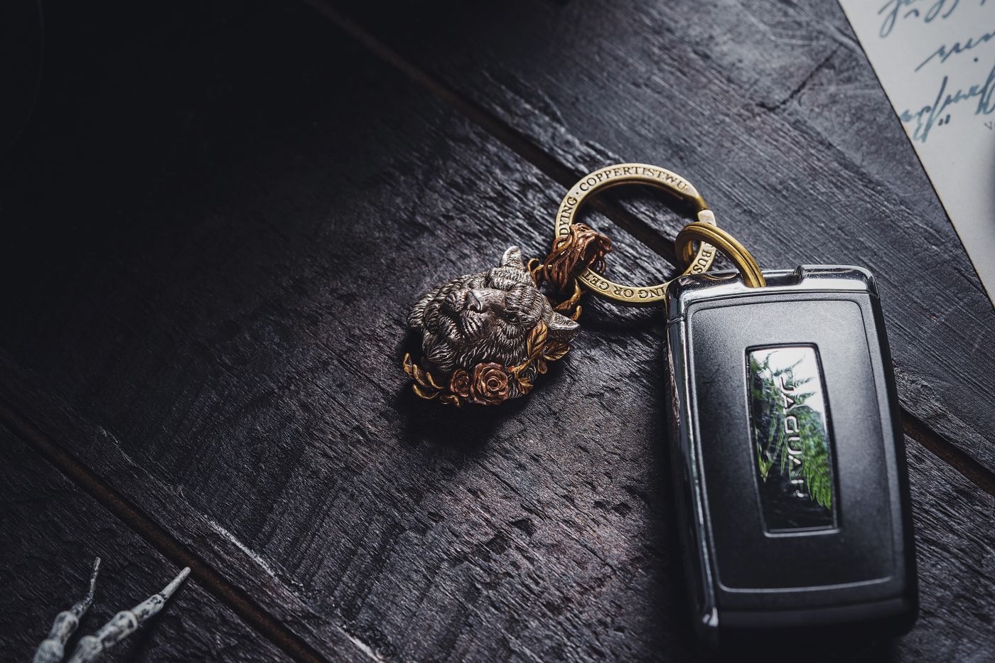 alphabet keychain — Elegant silver lion keychain paired with a luxury car key on a dark wooden surface