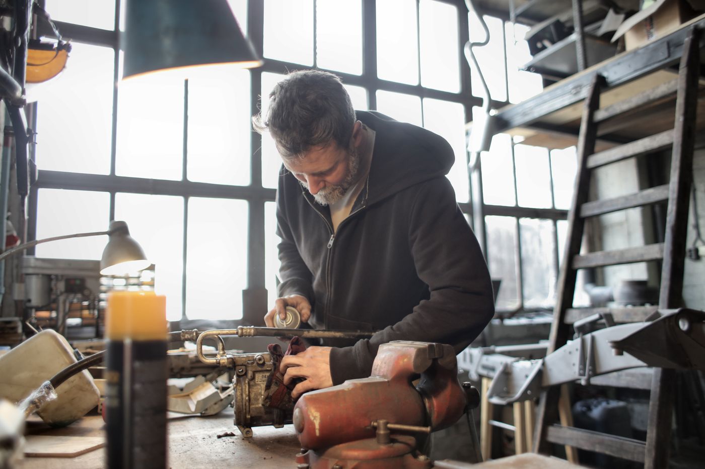 inkjet vs laser printer cost per page — Male craftsman in casual outfit fixing old rusty detail in workshop and using aerosol paint while standing at workbench 
