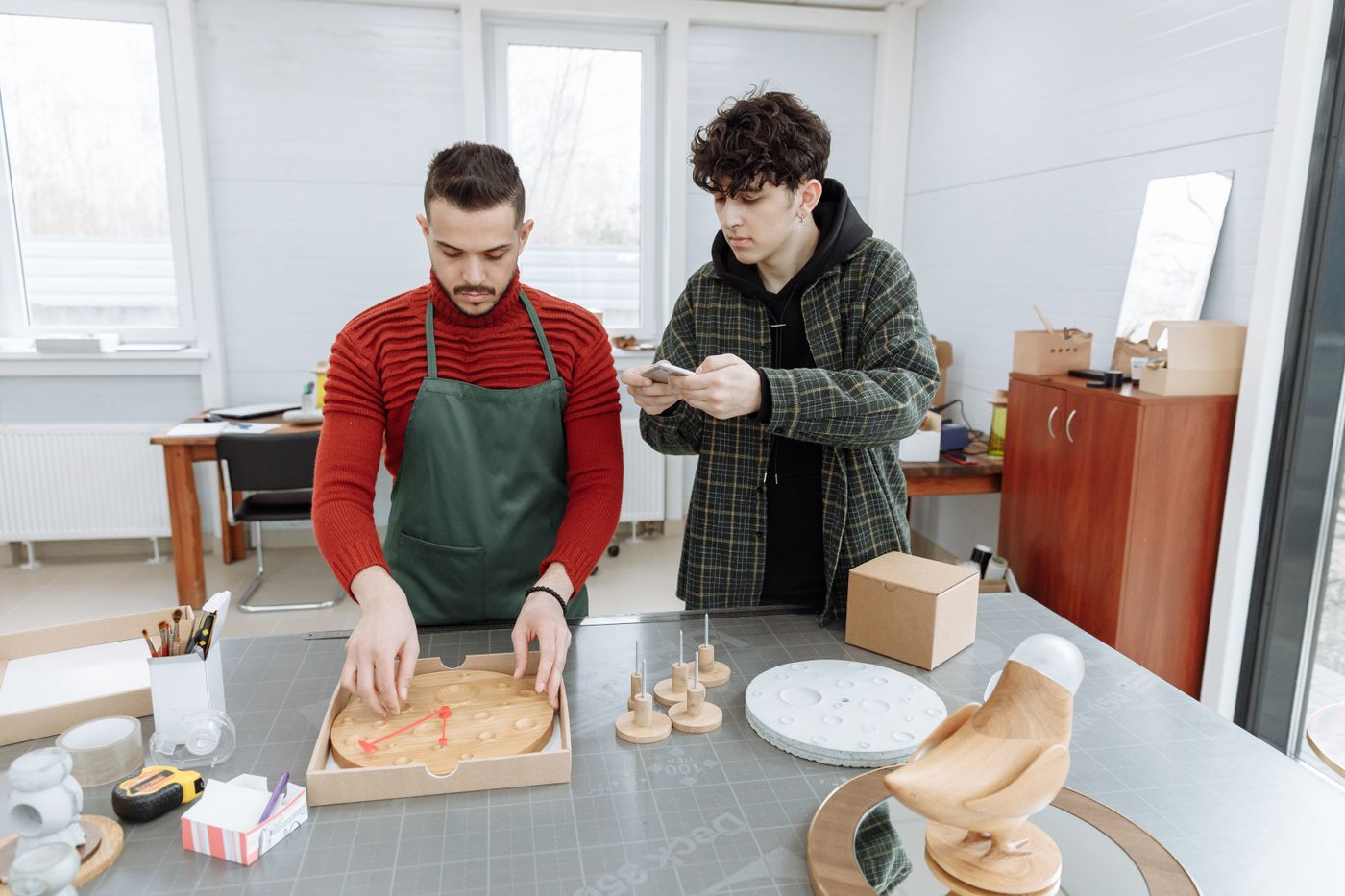 inkjet vs laser printer cost per page — Two men in a creative workspace assembling clocks, capturing industrial and craft elements